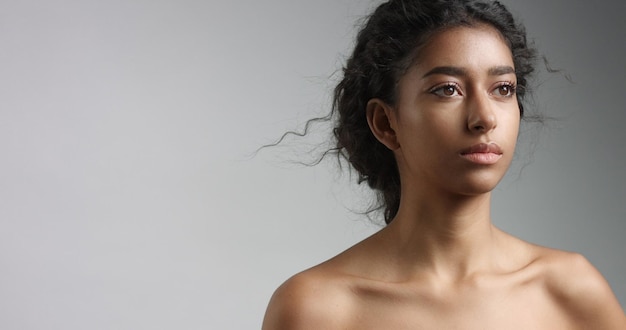 Free photo happy serene young woman with beautiful olive skin and curly hair ideal skin and brown eyes in studio