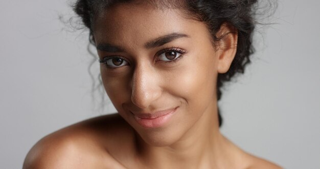 Happy serene young woman with beautiful olive skin and curly hair ideal skin and brown eyes in studio