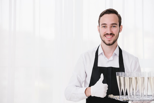 Happy servant carrying champagne glasses with copy space