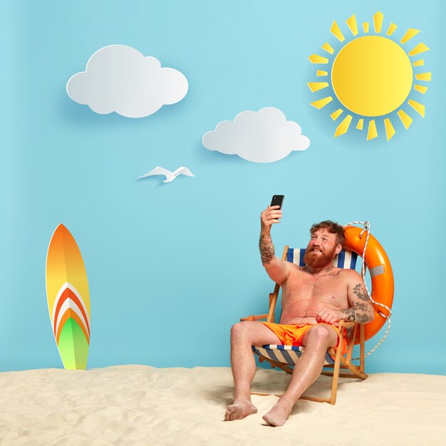 Happy shirtless bearded redhead man posing at the beach