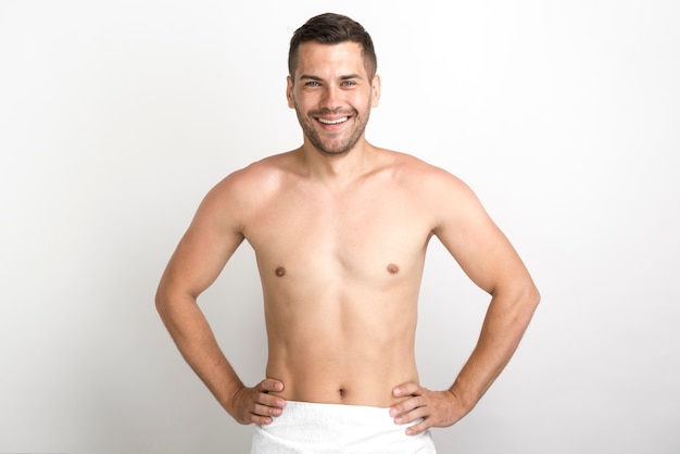 Happy shirtless man posing against white wall