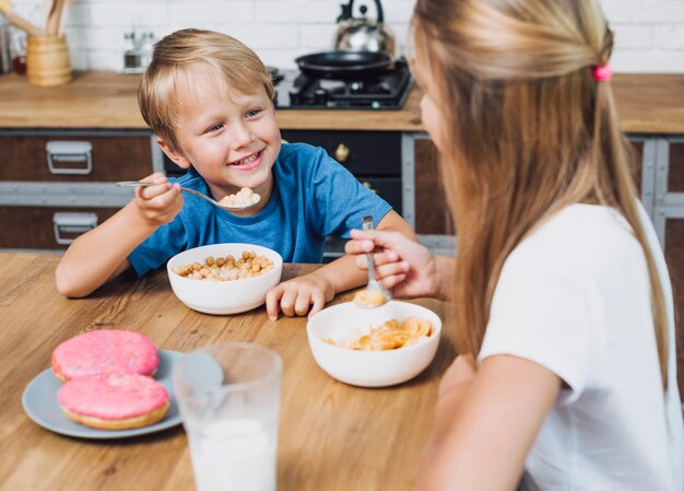 Happy siblings looking at each other while eating