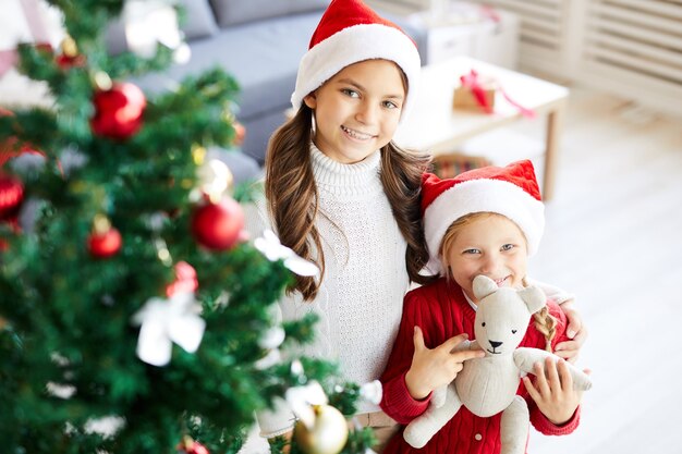 幸せな姉妹の女の子とインテリアのリビングルームに飾られたクリスマスツリー