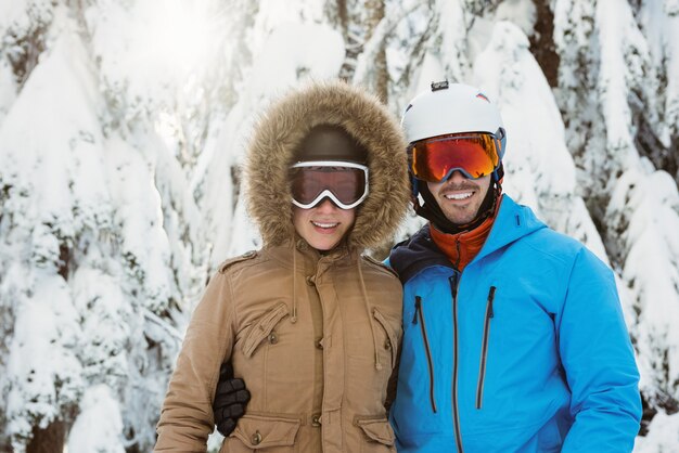 雪景色に立っている幸せなスキーヤーのカップル