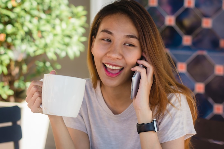 無料Photo 幸せな笑顔アジアのビジネス女性話して携帯電話を使用してカフェに座って、コップのカップを