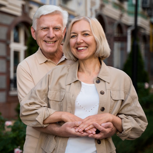 Free photo happy and smiley elder couple posing together while taking a walk in the city