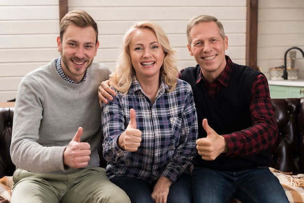 Foto gratuita famiglia felice e sorridente che propone mentre dando i pollici in su