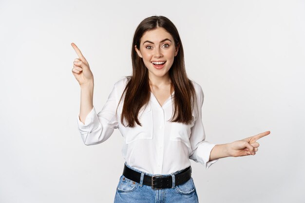 Happy smiling adult woman pointing sideways, showing two choices, products on sale logo or diagram, standing over white background