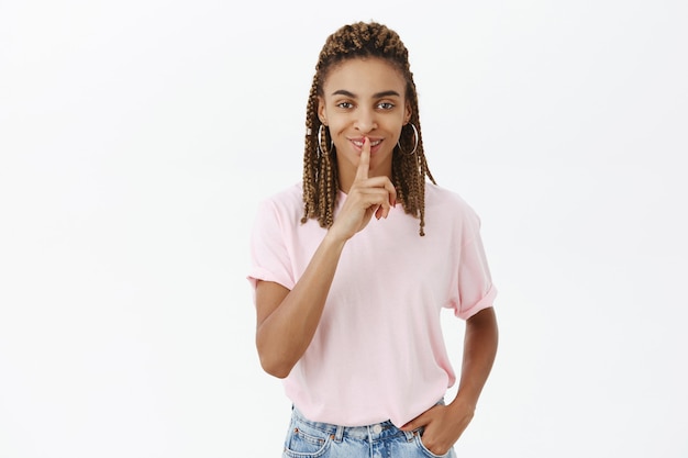 Free photo happy smiling african-american girl tell secret, shh gesture, shushing