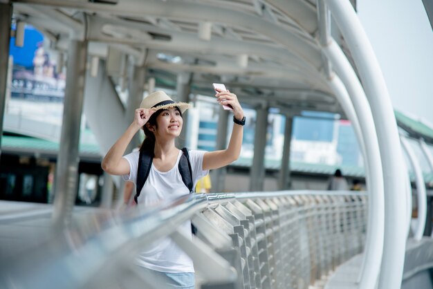 街背景でバックパックと幸せの笑みを浮かべてアジア学生少女