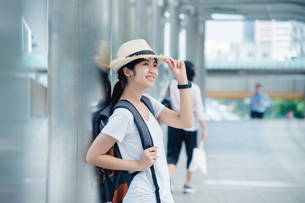 街背景でバックパックと幸せの笑みを浮かべてアジア学生少女