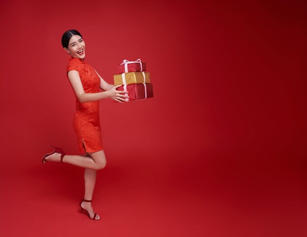 中国の旧正月を祝福するためのギフトボックスを与える赤い伝統衣装を着た幸せな笑顔のアジアの女性
