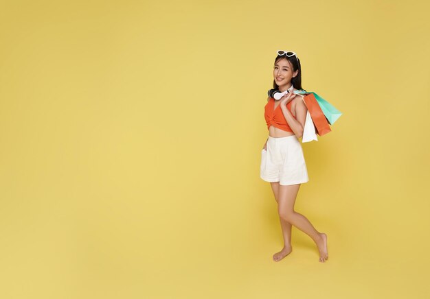 夏のドレスを着て夏の売り上げでショッピングバッグを握っている幸せな笑顔の魅力的なアジア人女性