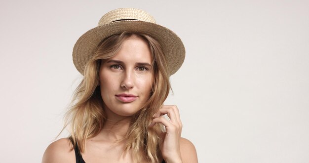 Happy smiling attractive model plays with a small cute straw hat isolated on white