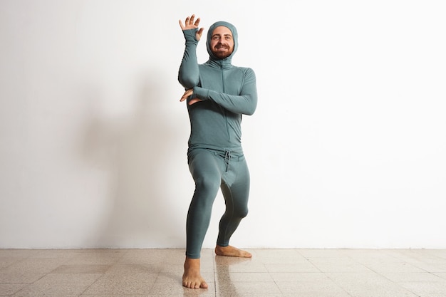 Happy smiling bearded fitted male wearing snowboarding thermal baselayer suite and posing like a ninja, isolated on white