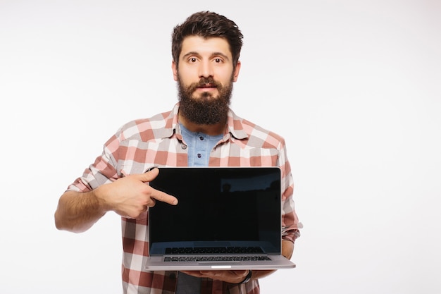 Happy smiling bearded man holding blank screen laptop computer isolated over white wall