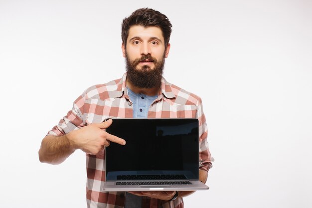 Счастливый улыбающийся бородатый мужчина держит пустой экран портативного компьютера, изолированного над белой стеной