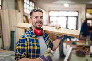 Free photo happy smiling carpenter holding wood material and thumbs up in his carpentry workshop