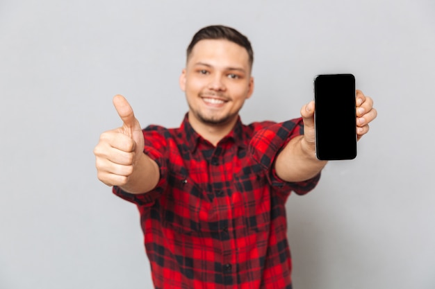 Happy smiling casual man holding blank screen mobile phone