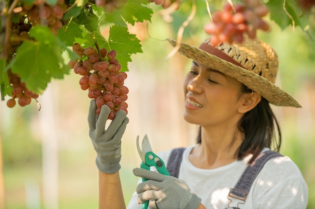 Бесплатное фото Счастливая улыбающаяся веселая женщина-виноградник в комбинезоне и соломенной шляпе в фермерском платье