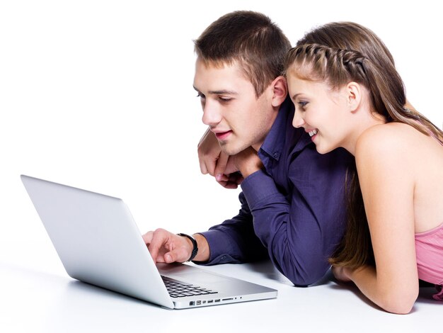Счастливая улыбающаяся пара с интересом смотрит на ноутбук - изолированные на белом