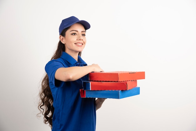 Happy smiling delivery girl in blue uniform with takeaway pizza boxes over white background. High quality photo