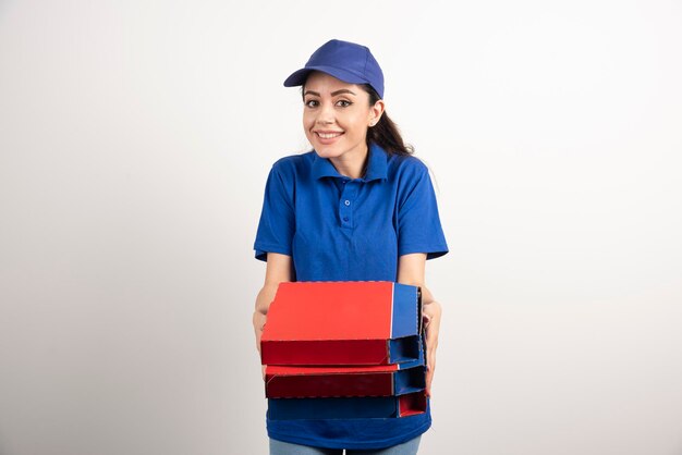 Happy smiling delivery girl in blue uniform with takeaway pizza boxes over white background. High quality photo