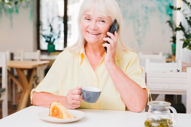 電話で話している幸せの笑みを浮かべて高齢者の女性