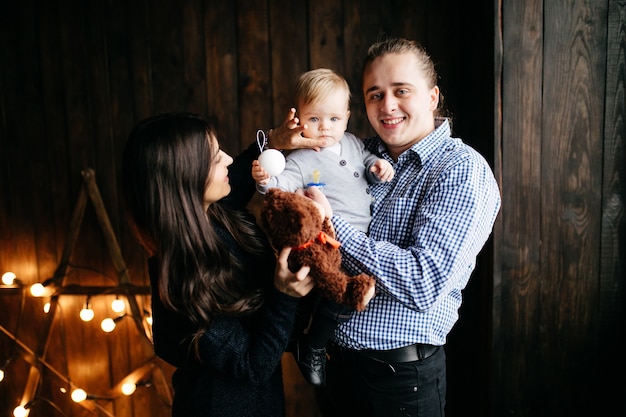 Happy smiling family at studio on background of the Christmas tree with gift