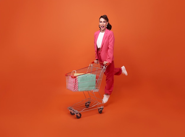 Free photo happy smiling fashionable woman with trolley and shopping bag walking shopping promotion summer sale