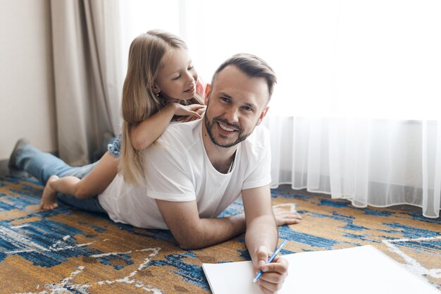 happy smiling father and his daughter drawing and doing home work indoor