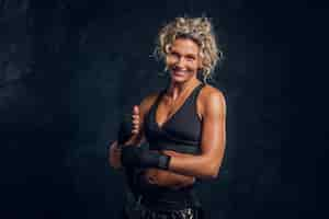 Free photo happy smiling female boxer is posing for photographer at dark photo studio.