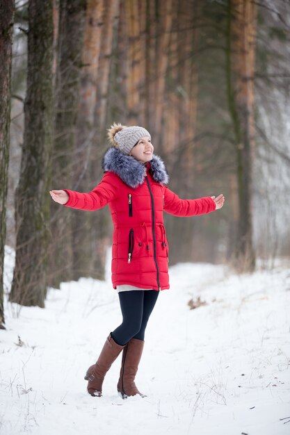 Happy smiling female in red winter jacket rejoicing outdoors