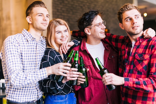 Happy smiling friends holding the green beer bottles in hand