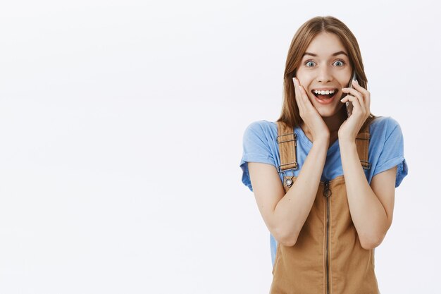 Happy smiling girl hear good news while talking on mobile phone