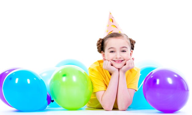 Happy smiling girl in yellow t-shirt  lying on the floor with colorful balloons - isolated on a white
