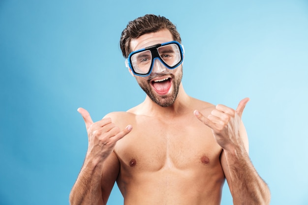 Happy smiling guy in swimming goggles showing thumbs up gesture