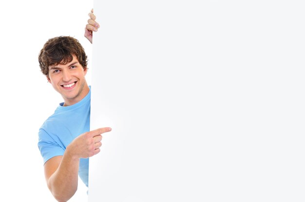 Happy smiling handsome  man look out from  banner and indicate by finger on it