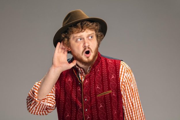 Free photo happy smiling man dressed in traditional austrian or bavarian costume gesturing isolated on grey