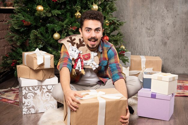Счастливый и улыбающийся человек, открывая свои подарки.