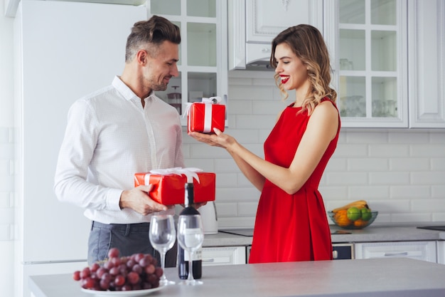 Счастливый улыбающийся мужчина и женщина, давая друг другу подарок на праздник