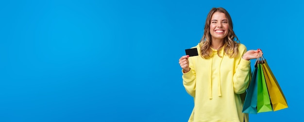 Free photo happy smiling pretty girl using her credit card deposit money for shopping holding bags with clothes