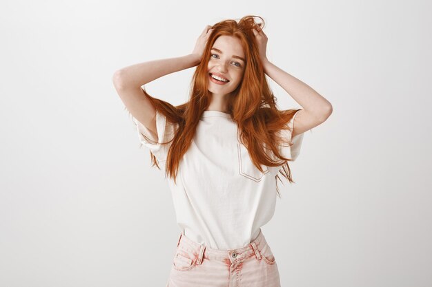 Happy smiling redhead girl touching her hair