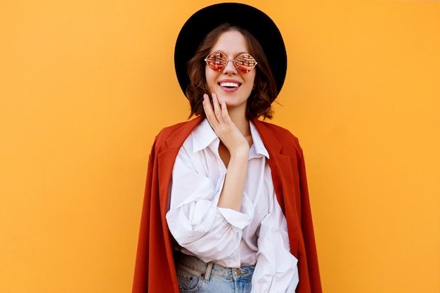 Happy smiling short haired girl posing over yellow wall. Warm colors. positive mood.