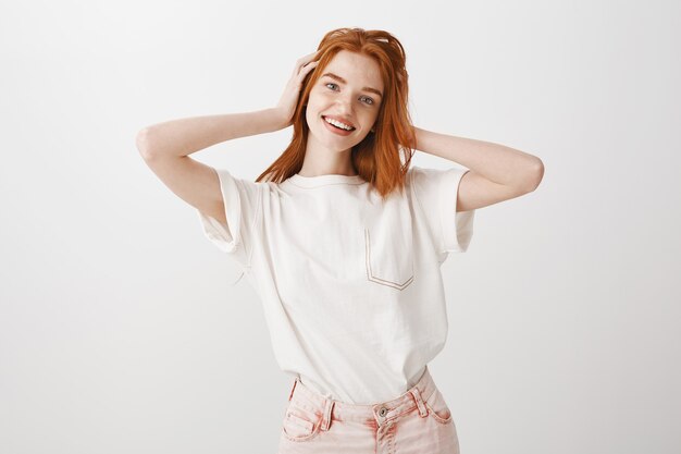 Happy smiling, stylish redhead girl touching her hair