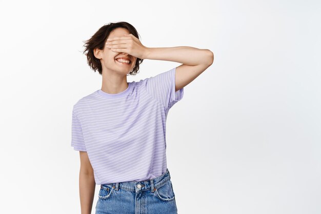 Happy smiling woman close her eyes, standing against white background.