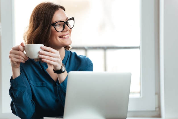 Donna sorridente felice che tiene tazza di caffè