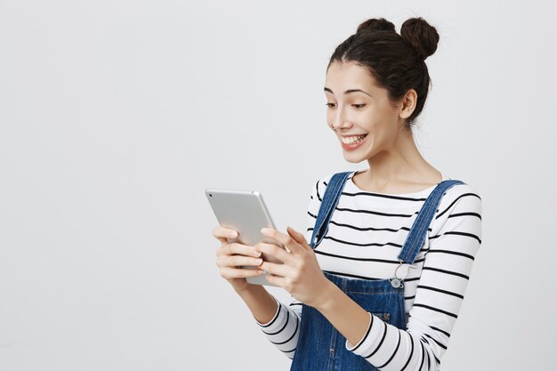 Счастливая улыбающаяся женщина, смотрящая на дисплей цифрового планшета