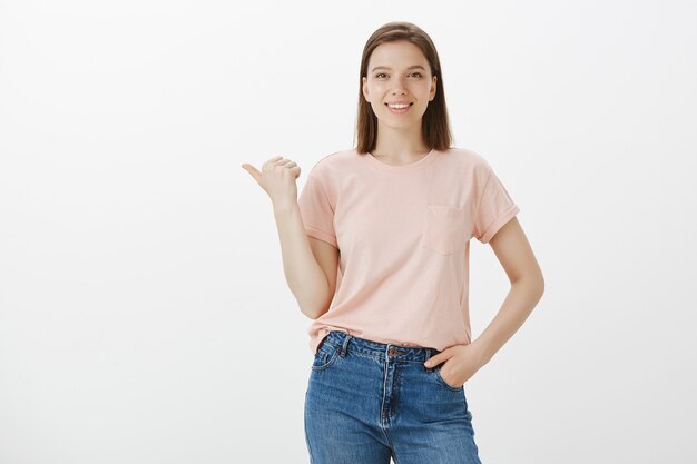 Happy smiling woman showing promo, pointing upper left corner