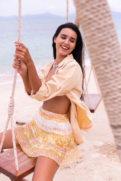 Happy smiling woman on swing at beach,day warm light.